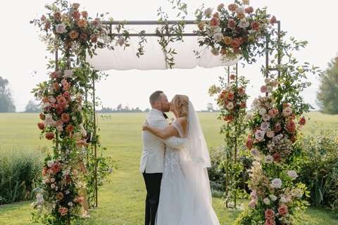Couple kissing under beautiful display of flowers